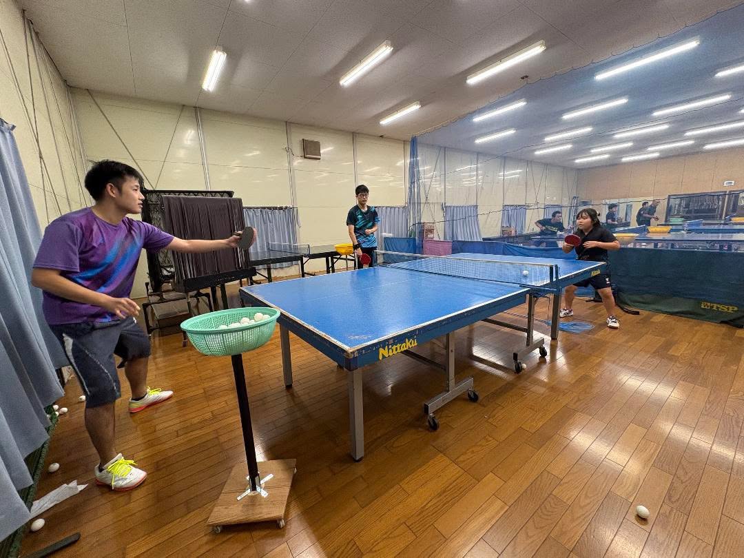 紫色のシャツを着た指導者が球出しをする練習風景